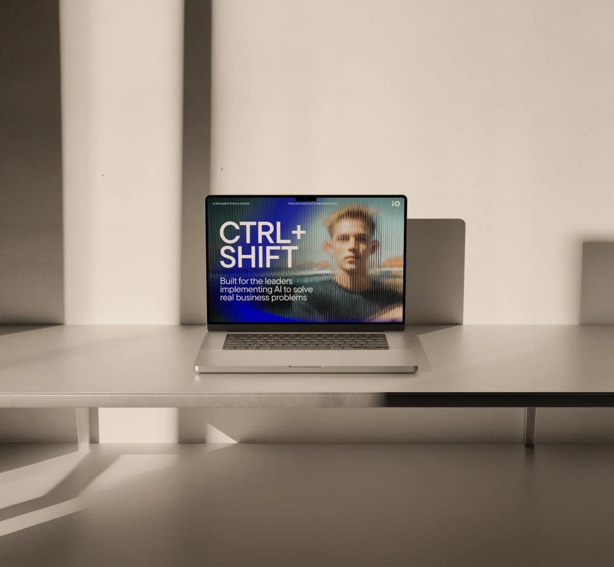 En laptop på ett bord visar en skärm med texten "CTRL+SHIFT" och "Built for the leaders implementing AI to solve real business problems" mot en bakgrund med en suddig bild av en person.